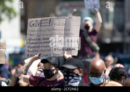Ein männlicher Protestor hält ein Schild mit Vorschlägen für wohltätige Zwecke Spenden zur Unterstützung der Black Lives Matter Bewegung bei Ein Protest in London Stockfoto