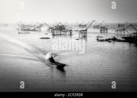 Schwarz-Weiß-Bild der traditionellen quadratischen Netzgeräte bei Sonnenaufgang in Pakpra Canal, Phatthalung, Thailand Stockfoto