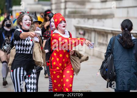 Demonstranten, die als Clowns verkleidet sind, geben während eines Extinction Rebellion Protestes in Westminster, London, gefälschtes Geld außerhalb des HM Treasury Gebäudes aus. Die Umweltkampagnengruppe hat Veranstaltungen geplant, die an mehreren Sehenswürdigkeiten der Hauptstadt stattfinden sollen. Stockfoto