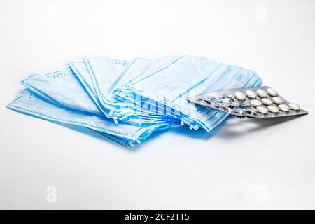 Medizinische Hygienemasken und Pillen in einer Blisterpackung liegen auf weißem Hintergrund Stockfoto