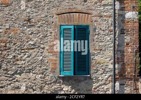 Italienisches Fenster mit hölzernen Fensterläden in einer Ziegelwand Stockfoto