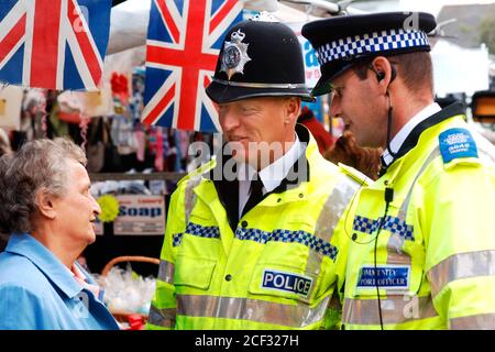 Polizist und Community Support Officer unterhalten sich mit einer älteren Frau auf dem lokalen Markt; Knaresborough; Scarborough; Yorkshire UK Stockfoto