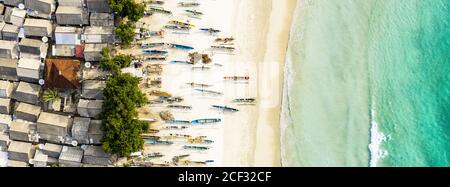 Atemberaubende Luftaufnahme eines Fischerdorfes mit Häusern und Booten an einem weißen Sandstrand, der von einem wunderschönen türkisfarbenen Meer umspült wird. Tanjung Aan Beach, Lombok. Stockfoto