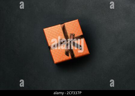 Geschenkbox mit Band auf dunklem Hintergrund. Braune Feiertagsverpackung für Geburtstag, Weihnachten, Hochzeit und andere festliche Veranstaltung. Draufsicht auf eine flache Anordnung Stockfoto