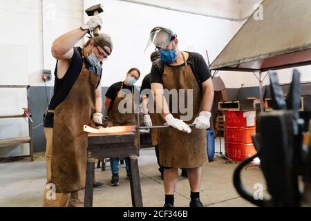 Schmiede schmieden Metalldetails, während sie heißes Eisen mit Hammer schlagen Stockfoto