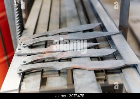 Nahaufnahme von handgefertigten scharfen Messern in Reihe gelegt Auf Metalltisch Stockfoto