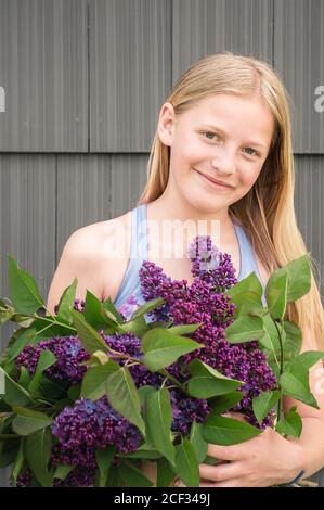 Tween Girl Holding Bündel von lila Flieder Blumen und lächelnd Stockfoto