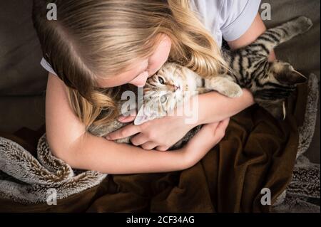 Junges Mädchen suchen nach unten Holding Kätzchen auf Brown Decke Stockfoto