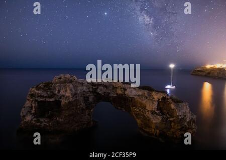 Panorama von Steinbogen und einem Segelboot mit der Milchstraße auf Mallorca. Nightscape-Konzept Stockfoto