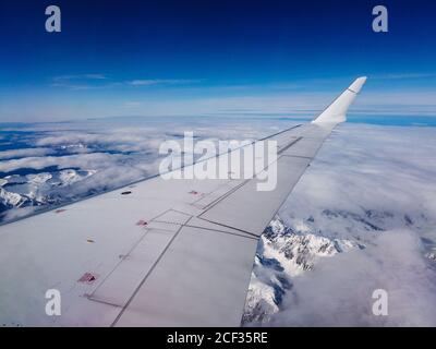 Flugflug. Flügel eines Flugzeuges, das über Bergen und Wolken fliegt Stockfoto