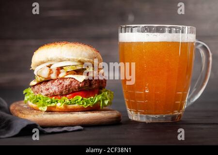 Zwei hausgemachte leckere Burger mit großem Rindfleisch, Käse, Tomaten, Speck und Salat und Lagerbierbecher Stockfoto