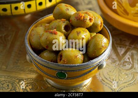 Traditionelle würzige grüne marokkanische Oliven in einer dekorativen Schüssel als Eine Beilage an einem Messingtisch Stockfoto