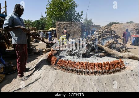 NIGER, Dorf Namaro, Fleischgrill auf dem ländlichen Markt, Fleischspieß, Ziegenfleisch auf Holzstäbchen Grillen um Feuer / Markttag, Fleisch Grillstand, Fleischspiesse Stockfoto