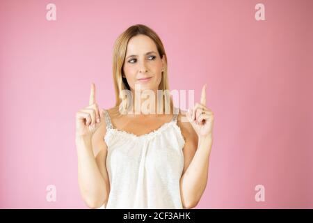 Schöne Frau mit den Fingern nach oben Geste auf rosa Hintergrund Stockfoto