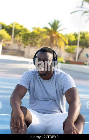 Junger schwarzer Mann lächelt und trägt Kopfhörer Stockfoto
