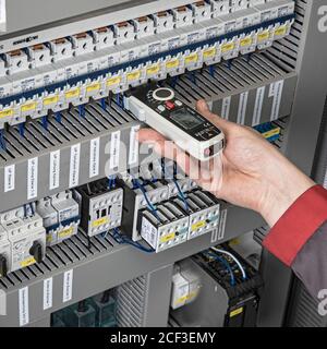 Elektriker, der mit einem Strommessmultimeter in einem Schaltschrank misst Stockfoto