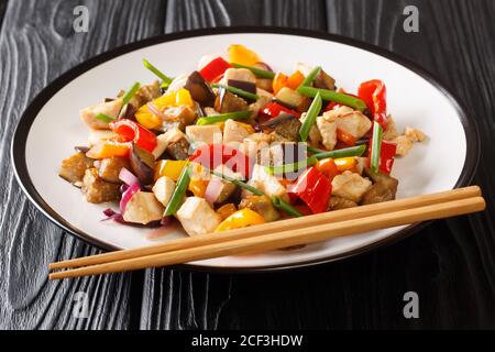 Servieren von gebratenem Huhn und Gemüse mit Auberginen, Paprika und Zwiebeln in einer würzigen Sojasauce close-up in einem Teller auf dem Tisch. Horizontal Stockfoto