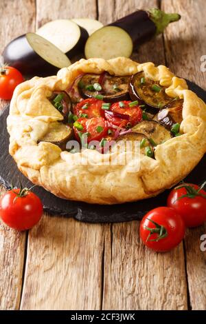 Auberginen Galette Kuchen mit Tomaten, Zwiebeln und Kräutern Nahaufnahme auf einem Schieferbrett auf dem Tisch. Vertikal Stockfoto