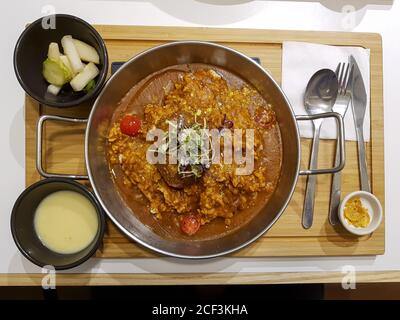 Hühnerfleisch Curry Reis in Korea. Beliebtes asiatisches Essen gemischt mit indischem, japanischem und koreanischem Stil. Serviert mit Maissuppe und eingelegter Gurke und Rettich. Stockfoto