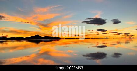 Wunderschöner Sonnenuntergang. Orange schöner Sonnenuntergang Himmel über Salzsee in Uyuni, Bolivien. Surreale Landschaft von Salzflächen. Magische Spiegelung des Himmels im Wasser. Stockfoto