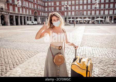 Junge touristische Frau trägt schützende Gesichtsmaske glücklich und aufgeregt In Plaza Mayor Madrid Spanien genießen Urlaub in Europa nach Ausbruch des Coronavirus Stockfoto