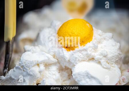 Makro Nahaufnahme von Zitrone Geschmack gelbe Früchte und weiße Gelato Eis mit Schaufel auf dem Display in Café-Shop in Italien, Italienisch Stockfoto