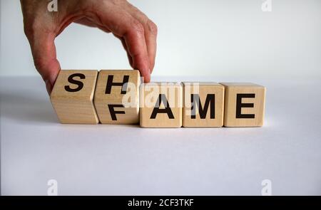Hand dreht Würfel und ändert das Wort Scham zu Ruhm. Schöner weißer Hintergrund. Geschäftskonzept. Speicherplatz kopieren. Stockfoto