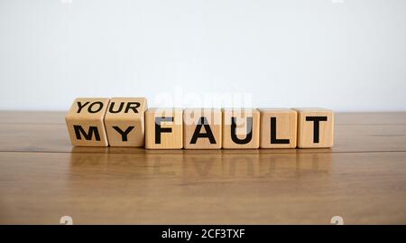 Einen Würfel gedreht und den Ausdruck 'Mein Fehler' in 'Ihr Fehler' geändert. Schöner Holztisch, weißer Hintergrund, Kopierraum. Geschäftskonzept. Stockfoto