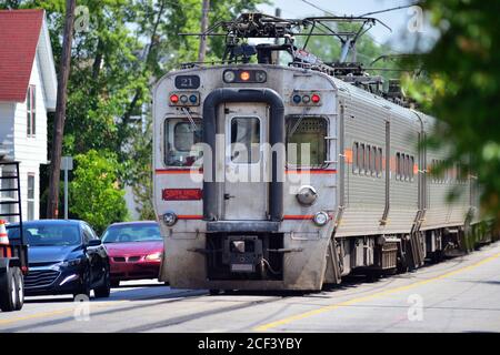 Michigan City, Indiana, USA. Ein South Shore Linie Pendlerzug in der Mitte der 11th Street und Verkehr in Michigan City, Indiana. Stockfoto