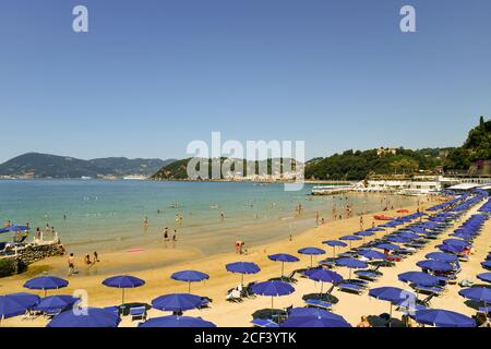 Hochwinkel Blick auf einen Sandstrand mit Reihen von Sonnenschirmen am Ufer des Golfs der Dichter in einem sonnigen Sommertag, Lerici, La Spezia, Ligurien, Italien Stockfoto