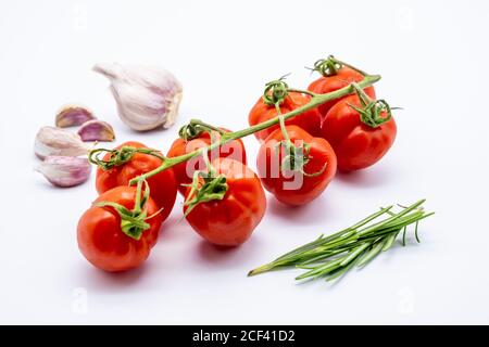 Rote Kirschtomaten mit Knoblauchzehen und Rosmarin auf weiß Hintergrund Stockfoto
