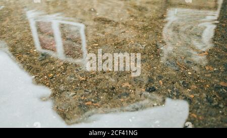 Ein Pflastersteingebäude, das sich in einem Puddle auf einem regnerischen Gebäude widerspiegelt Tag Stockfoto