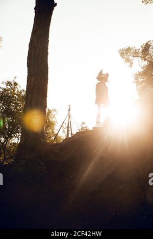 Unerkennbarer Mountainbiker Sportler, der während der Bergtour auf dem Hügel steht Sonnenuntergang im Wald Stockfoto