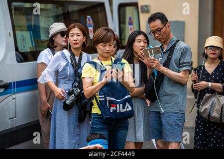 Florenz, Italien - 30. August 2018: Ostasiatische Familiengruppe von Touristen auf der Straße in der historischen Stadt auf der Suche nach dem Weg mit Fila Tasche Stockfoto