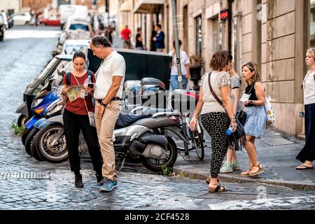 Rom, Italien - 4. September 2018: Menschen paar Touristen stehen in der Stadt Gasse Straße Blick auf Karte für verlorene Richtungen offen mit geschäftigen Straße tr Stockfoto