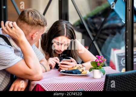 Rom, Italien - 4. September 2018: Italienischer Restauranttisch und junger Mann Frau Touristen Paar Nahaufnahme sitzen draußen im Café Blick auf Telefon mit Kamera Stockfoto