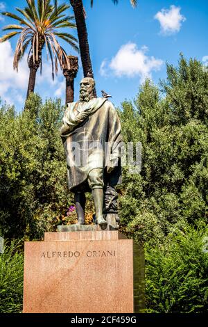 Rom, Italien - 4. September 2018: Historischer grüner Park an der Via della Domus Aurea Straße mit Statue von Alfredo Oriani und Zeichen und Vögel blauen Himmel Stockfoto