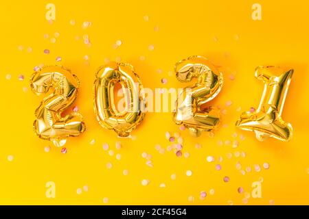 Frohes neues Jahr 2021 Feier. Leuchtend goldene Ballons mit Glitzersternen auf gelbem Hintergrund. Weihnachten und Neujahr feiern. Stockfoto