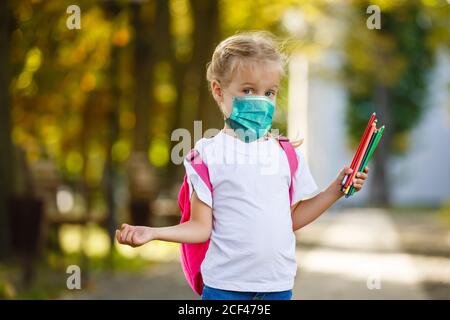 Kind Mädchen Schüler tragen schützende medizinische Gesichtsmaske in der Schule, Epidemie, Verbreitung von Coronavirus, Covid-19, Schulmädchen mit Maske, um Corona zu verhindern Stockfoto