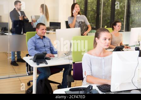 Junge seriöse Geschäftsleute arbeiten und kommunizieren zusammen in modernen Großraumbüro Stockfoto
