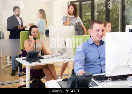 Positive Erwachsene Geschäftsleute arbeiten und kommunizieren zusammen in modernen Großraumbüro Stockfoto