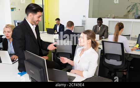 Gut aussehender bärtiger Mann reden und flirten mit attraktiven lächelnde Frau, die in co-Arbeitsbereich Stockfoto