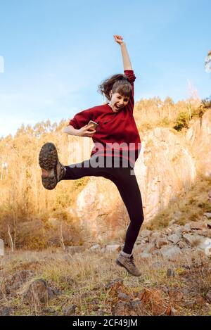 Junge attraktive Hipster mit upped Hand Musik auf Handy hören Telefon und Tanz zwischen Felsen Stockfoto