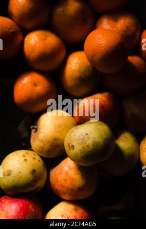 Von oben frische saftige Äpfel Mandarine mit Granatapfel und Orange Karotte auf schwarzer Oberfläche im Licht Stockfoto