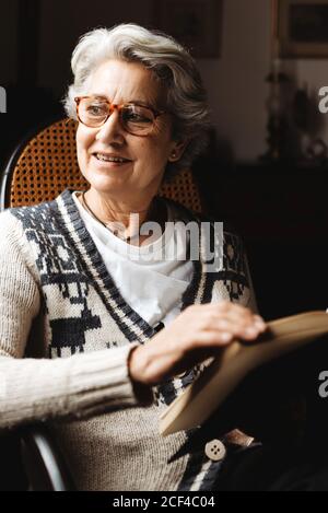 Ältere Frau liest mit Begeisterung am Fenster Stockfoto