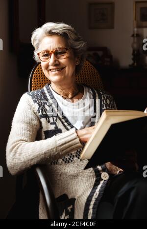 Ältere Frau liest mit Begeisterung am Fenster Stockfoto