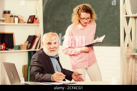 Student verwirrt durch einige Informationen. Student fragt Lehrer nach Aufgabe. Erzieher und Schüler, die Buch betrachten. Erläuterung des schwierigen Themas. Mathematische Aufgaben lösen. Schulkonzept. Hausaufgaben überprüfen. Stockfoto