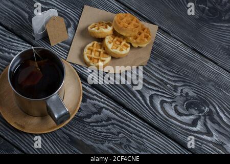 Tasse Tee und Waffeln. In der Nähe ist ein Teebeutel. Auf lackierten Brettern. Stillleben im Herbst. Stockfoto