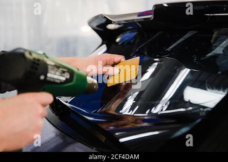 Autokunstönung. Arbeiter, der Farbfolie auf das Autofenster aufklebt Stockfoto