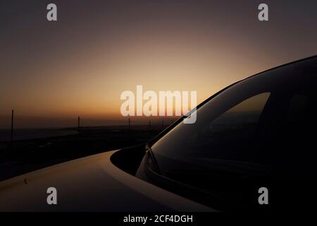 Malerischer Blick auf den Sonnenuntergang Himmel über dem Meer und geparktes Auto Abends Stockfoto